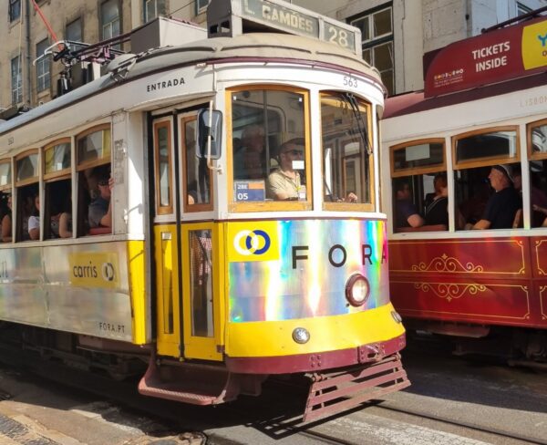 Two iconic trams passing each other on a street in Lisbon, with historic buildings in the background.