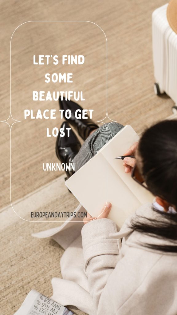 Overhead view of a traveler in a cream coat sitting on a light stone floor, writing in an open notebook with a white suitcase partly visible beside her and black ankle boots crossed in front. Overlaid text reads "LET’S FIND SOME BEAUTIFUL PLACE TO GET LOST" and "UNKNOWN" and "EUROPEANDAYTRIPS.COM"