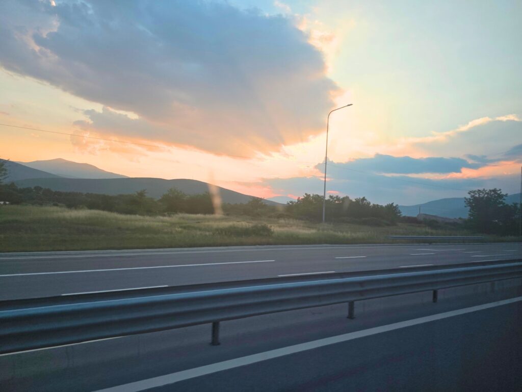 Sunset over mountains and grassy fields beside the motorway on the journey from Kosovo to Tirana.