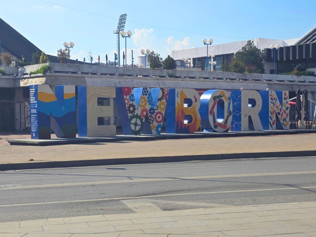 Colourfully painted NEWBORN monument in Pristina, with large freestanding letters beside the road.